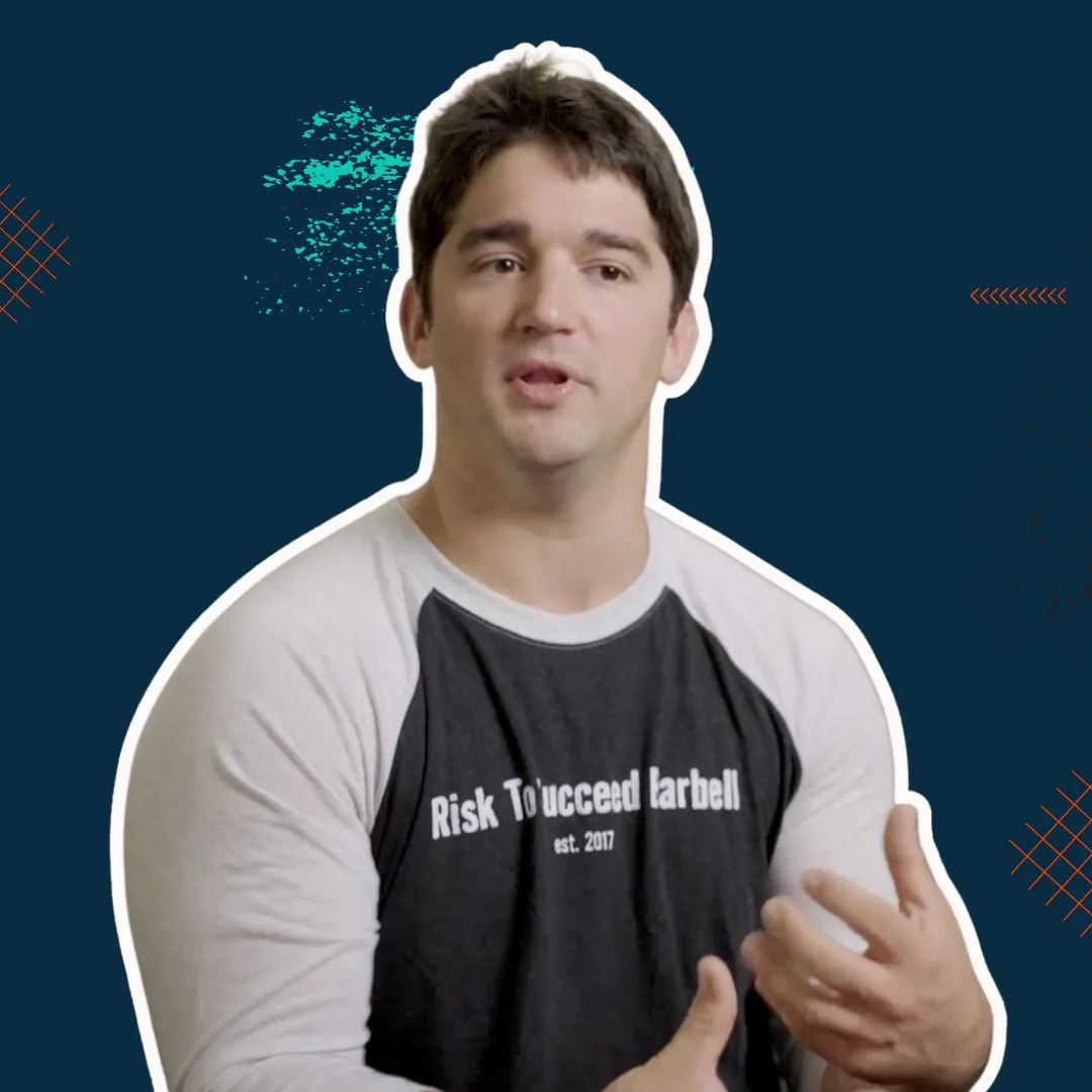 Man with short dark hair wearing a black and gray shirt that says 'Risk To'ucceed Barbell est. 2017' gesturing with his hands against a dark blue background with abstract graphic elements.