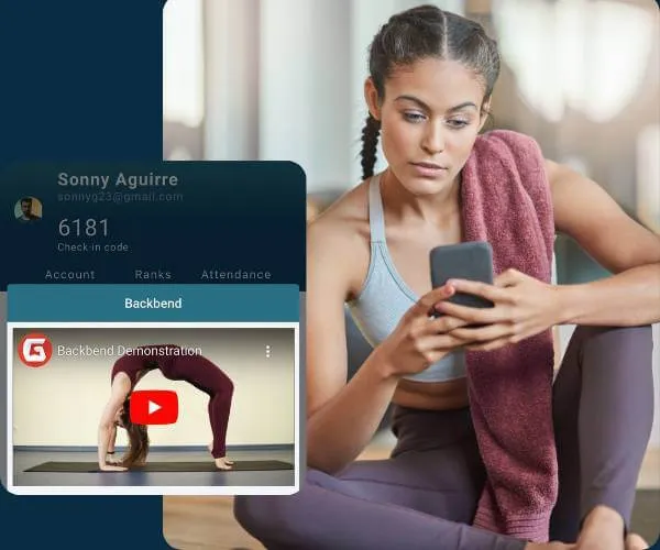 Woman in workout clothes sitting on the floor with a towel over her shoulder, looking at her phone, with a video thumbnail of a yoga backbend pose on screen.