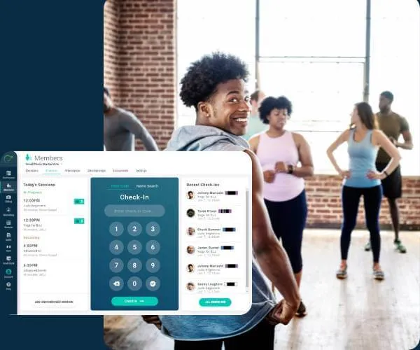 A smiling man with curly hair in a gray hoodie leads a diverse group in a fitness class inside a bright gym with brick walls and large windows.