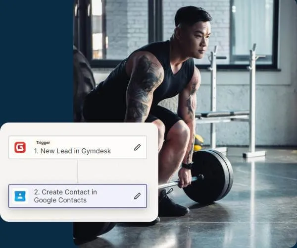 Man with tattoos performing a deadlift exercise in a gym with windows and weightlifting equipment.