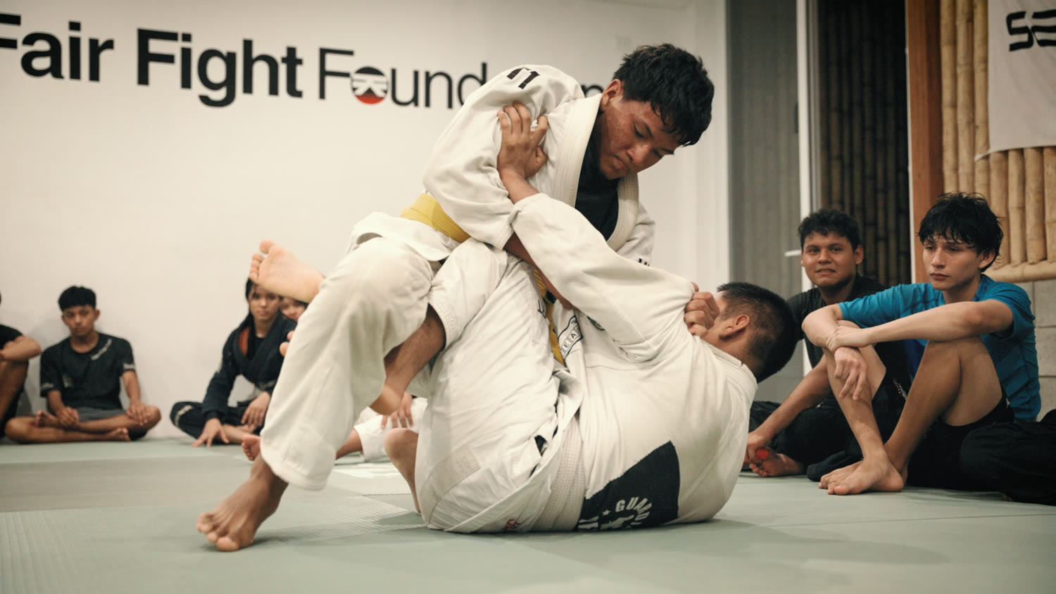 Two teenage Guardian Peru students rolling during a jiu-jitsu class.