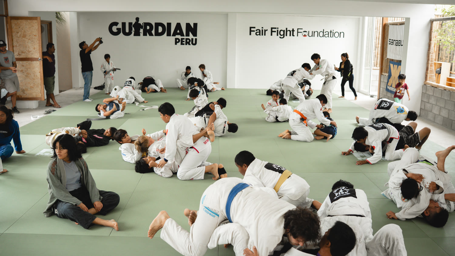 A full Guardian Peru youth jiu-jitsu class training together on the mat.