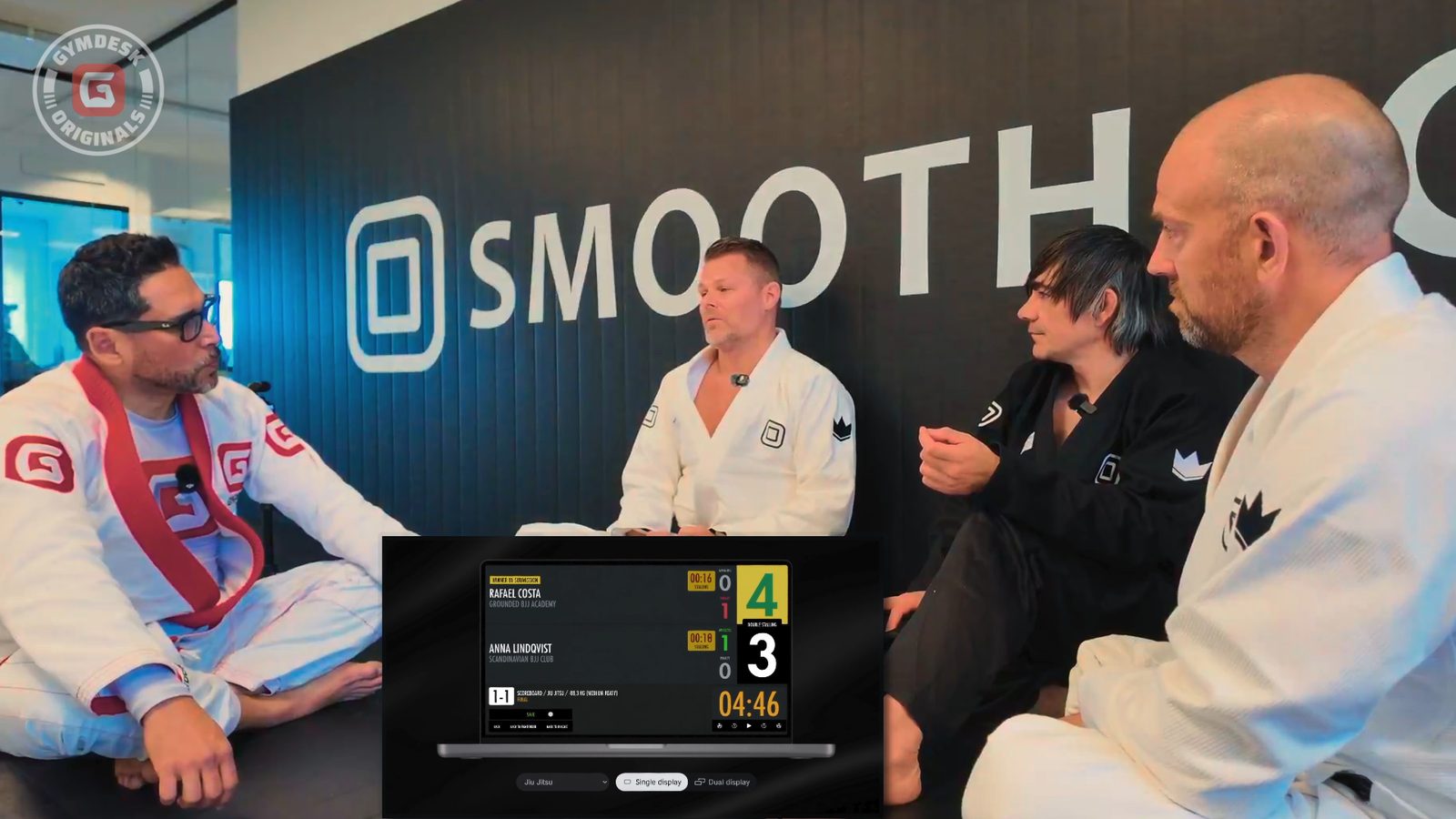 A Smoothcomp scoreboard on screen during the episode, with the match clock and points