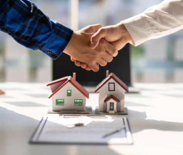 Handshake over miniature model houses representing a real estate agreement