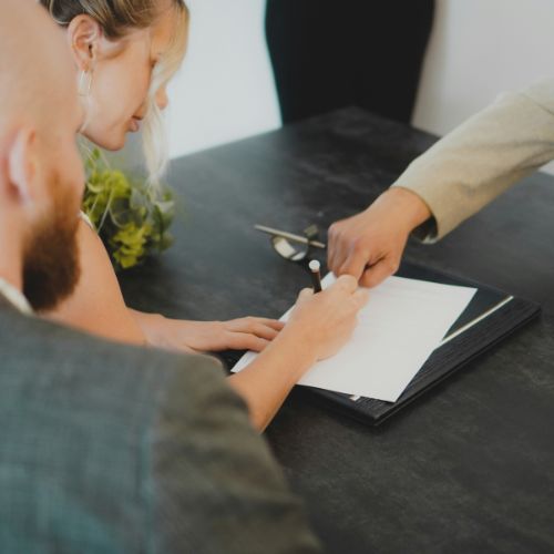 Couple signing home purchase paperwork with real estate agent.