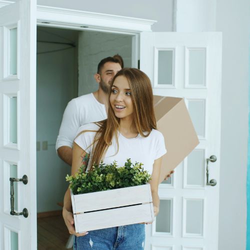 Young couple moving into a new home carrying boxes.