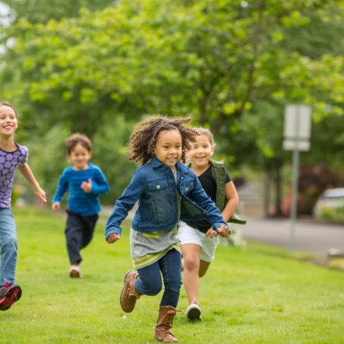 Kids running and playing outdoors in a neighborhood park.