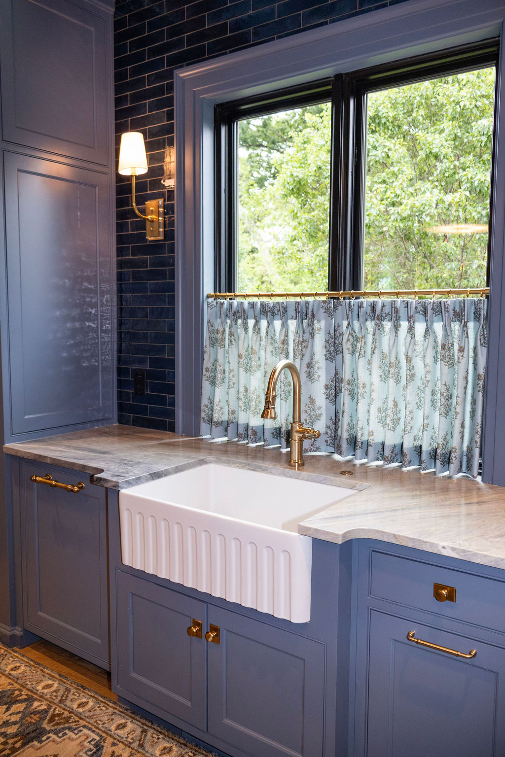 Modern kitchen with white marble countertop island, gray upholstered bar stools, dark wood cabinets, wall-mounted flat-screen TV, and wine cooler.