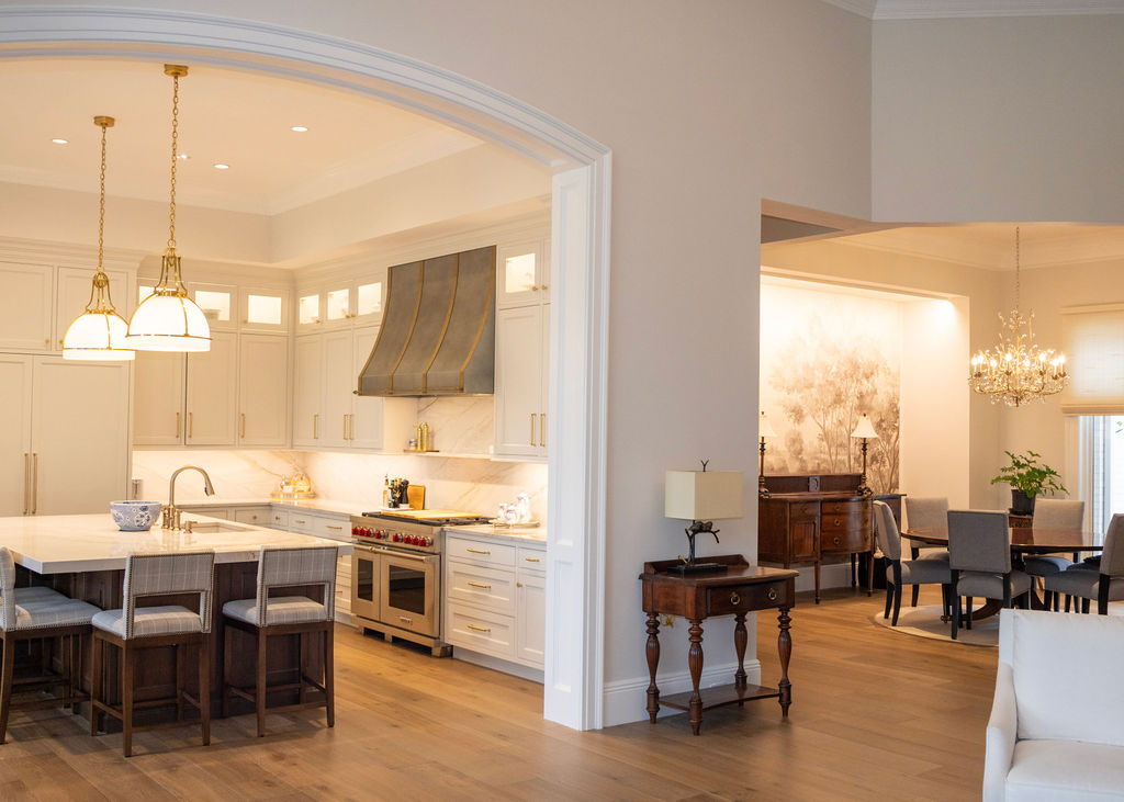 Modern kitchen with white marble countertop island, gray upholstered bar stools, dark wood cabinets, wall-mounted flat-screen TV, and wine cooler.