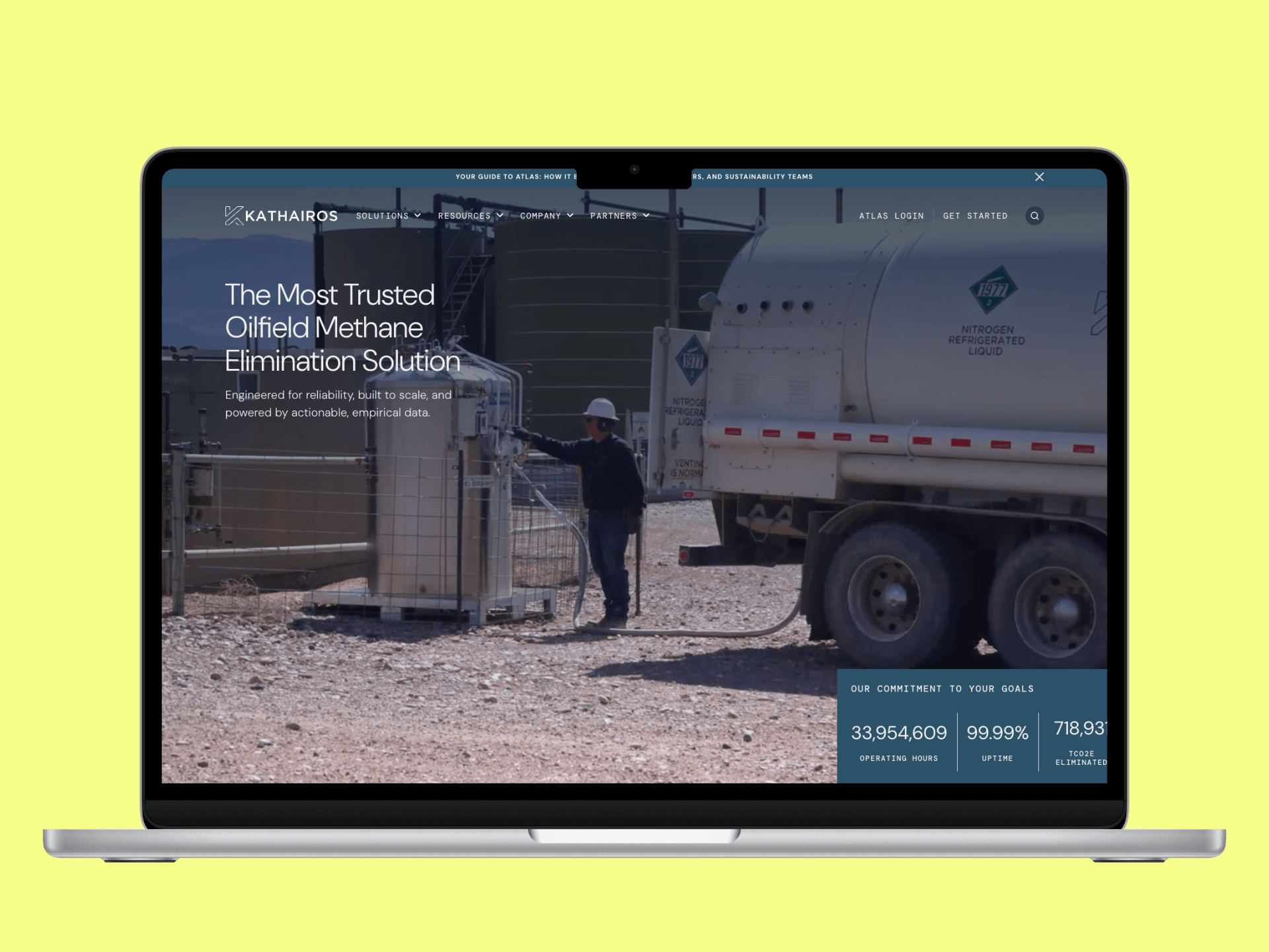 Laptop screen displaying Kathairos website with an oilfield worker operating nitrogen refrigerated liquid equipment outdoors.