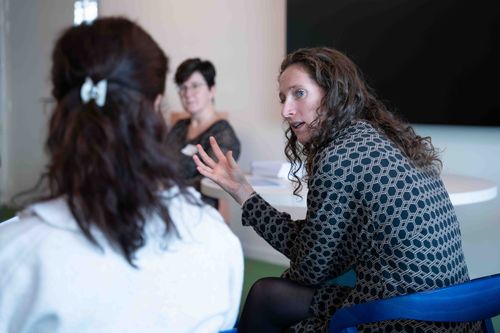 Three women sitting and having a serious discussion in a modern indoor setting.