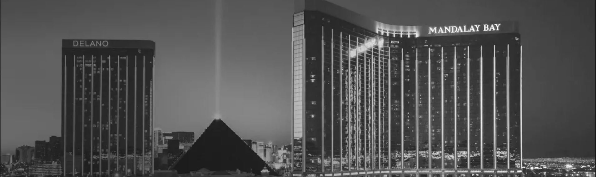 Night view of Las Vegas with Delano, Luxor pyramid light beam, and Mandalay Bay hotels illuminated.