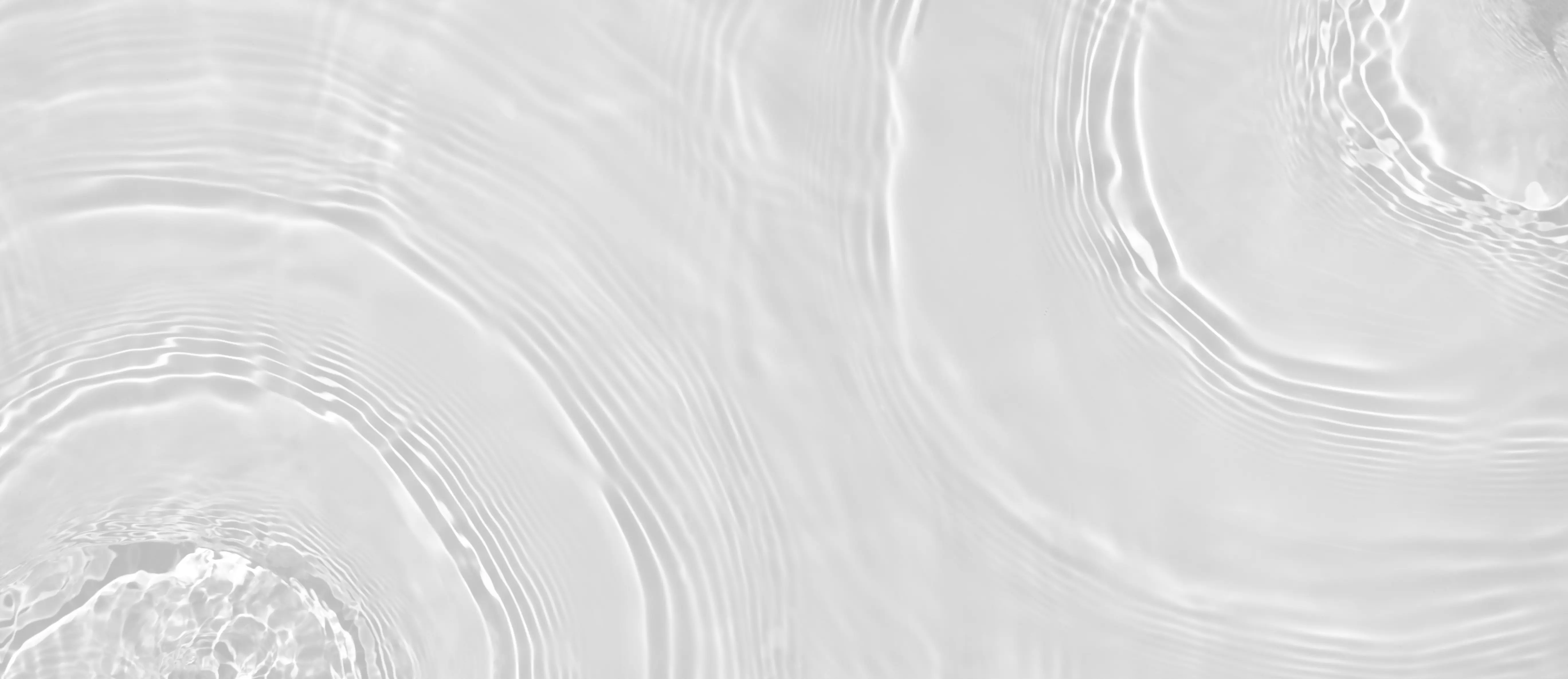 Close-up of water surface with gentle concentric ripples and subtle light reflections.