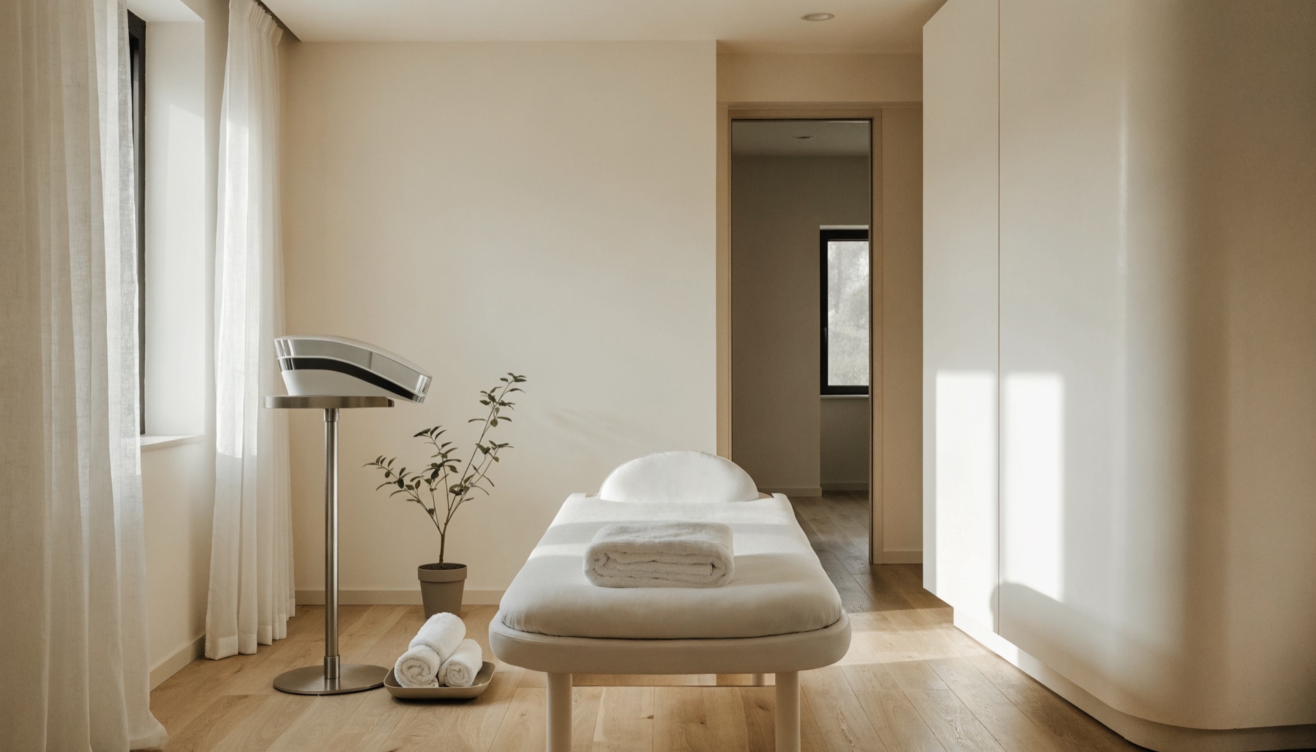 Modern minimalist aesthetic clinic treatment room with a white treatment bed and a skin tightening device