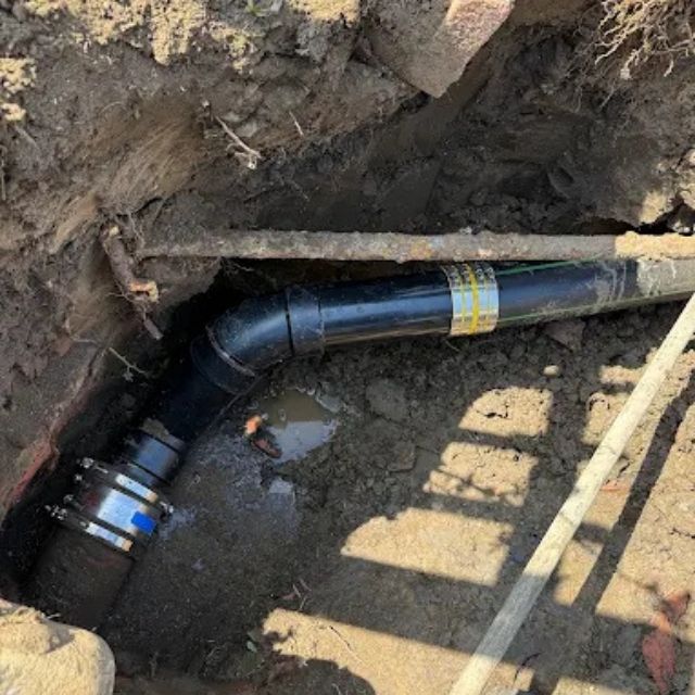 New ABS sewer pipe installed in trench during plumbing repair.