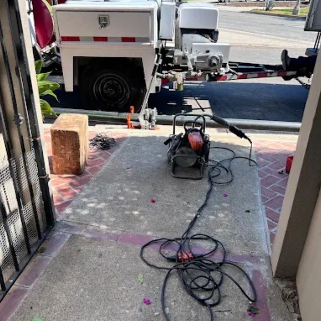 Plumbing truck and drain cleaning machine outside home for sewer service.