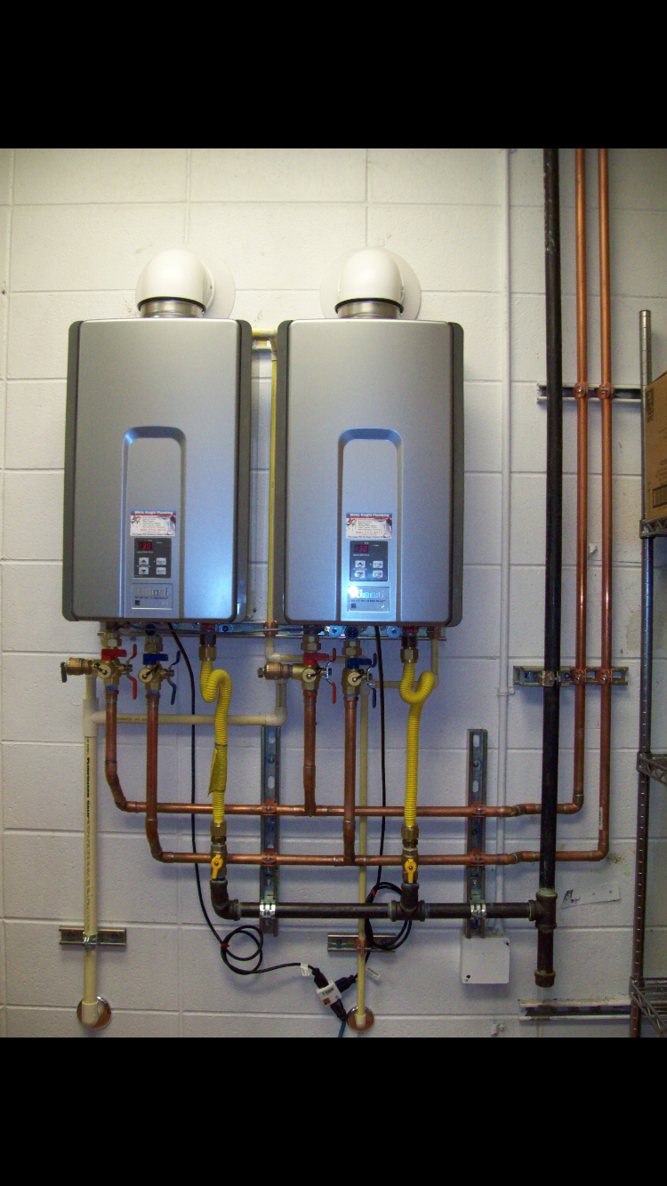 Commercial plumbing manifold with copper and steel pipes mounted on utility room wall.