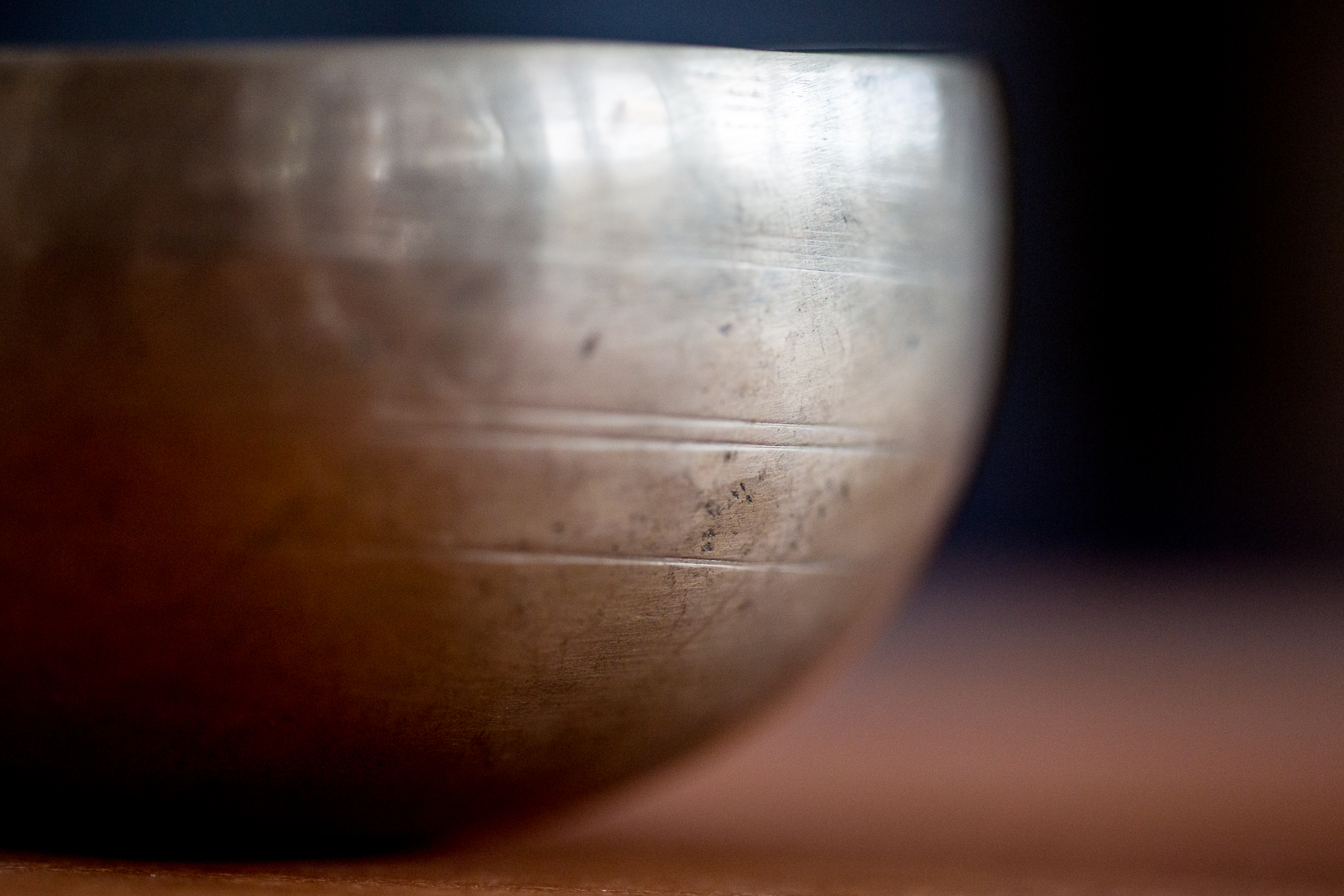 Close-up of a tarnished metallic bowl with scratches and a reflective surface.