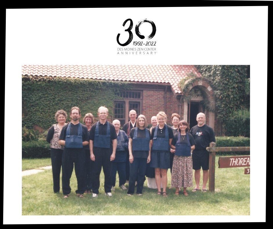 Group of thirteen people standing on grass in front of a brick building covered with ivy, commemorating the 30th anniversary of Des Moines Zen Center from 1992 to 2022.