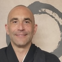 Man wearing a black robe with a large brushstroke circle artwork in the background.