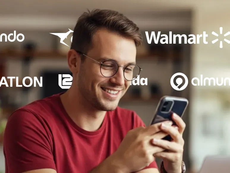 Smiling man with glasses in a red shirt using a smartphone indoors with blurred background and floating logos of various companies around him.
