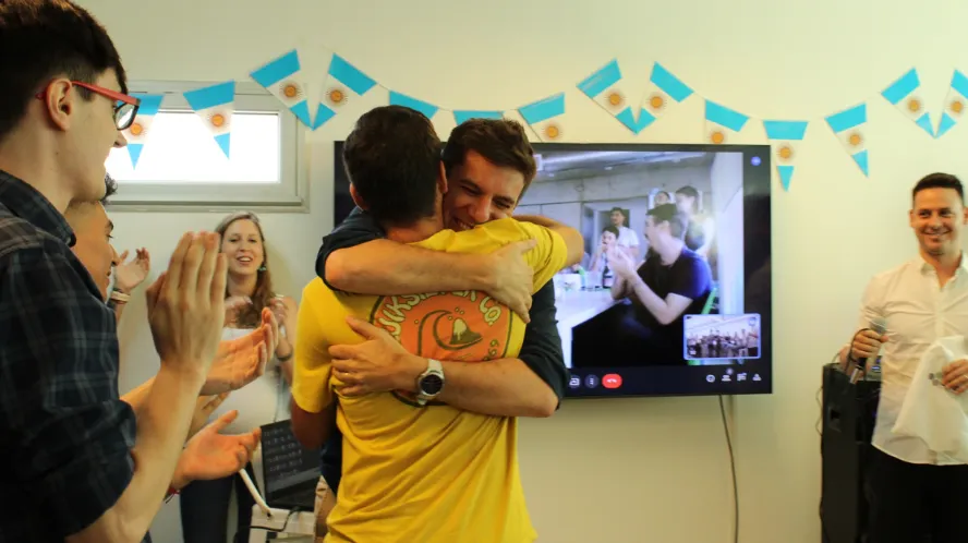 Four young professionals working on laptops and desktop computers with code displayed on monitors in a modern office.