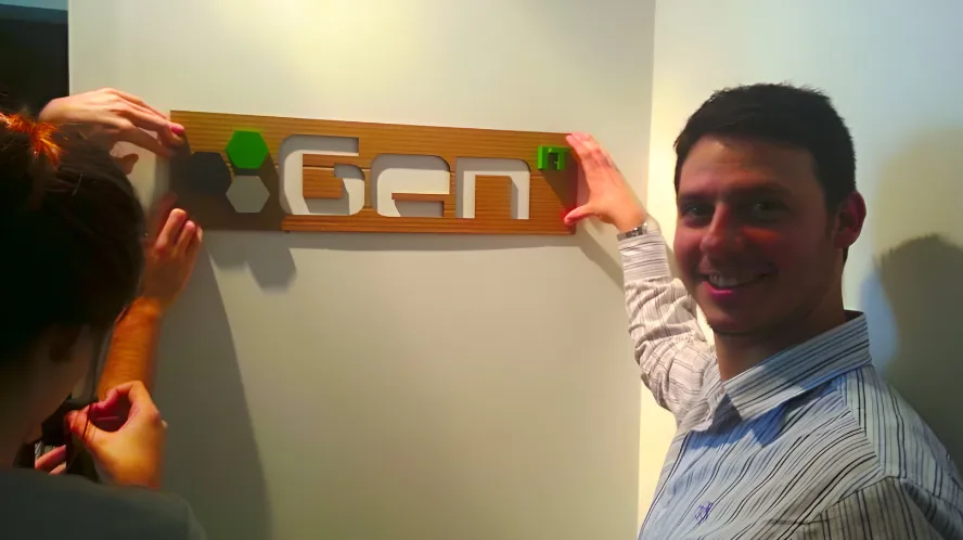 Four young professionals working on laptops and desktop computers with code displayed on monitors in a modern office.