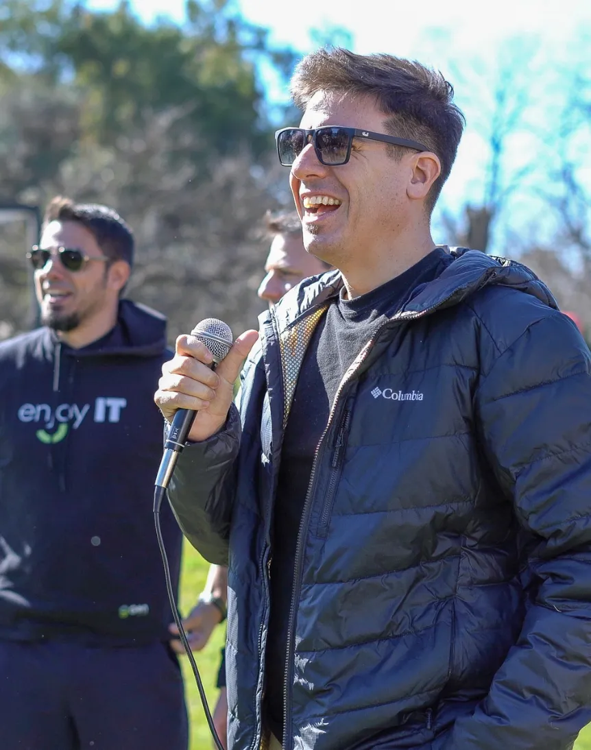 Two young adults collaborating in front of a glass wall covered with orange, blue, and white sticky notes, discussing ideas.
