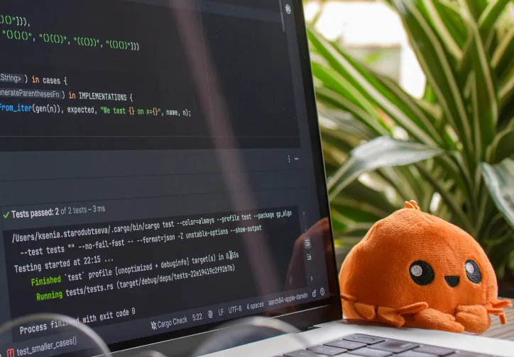 A man and woman standing and speaking to a group of seated young adults in a bright classroom with large windows.