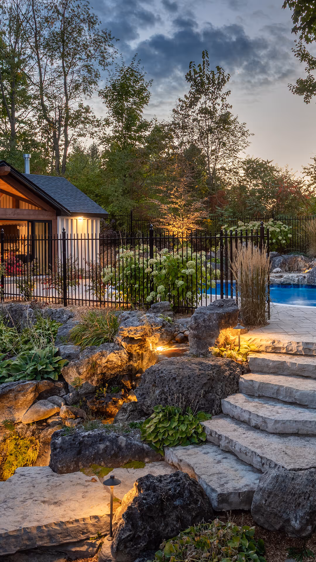 backyard landscaping with pool featureing waterfalls flowing into the pool, cabana with fireplace