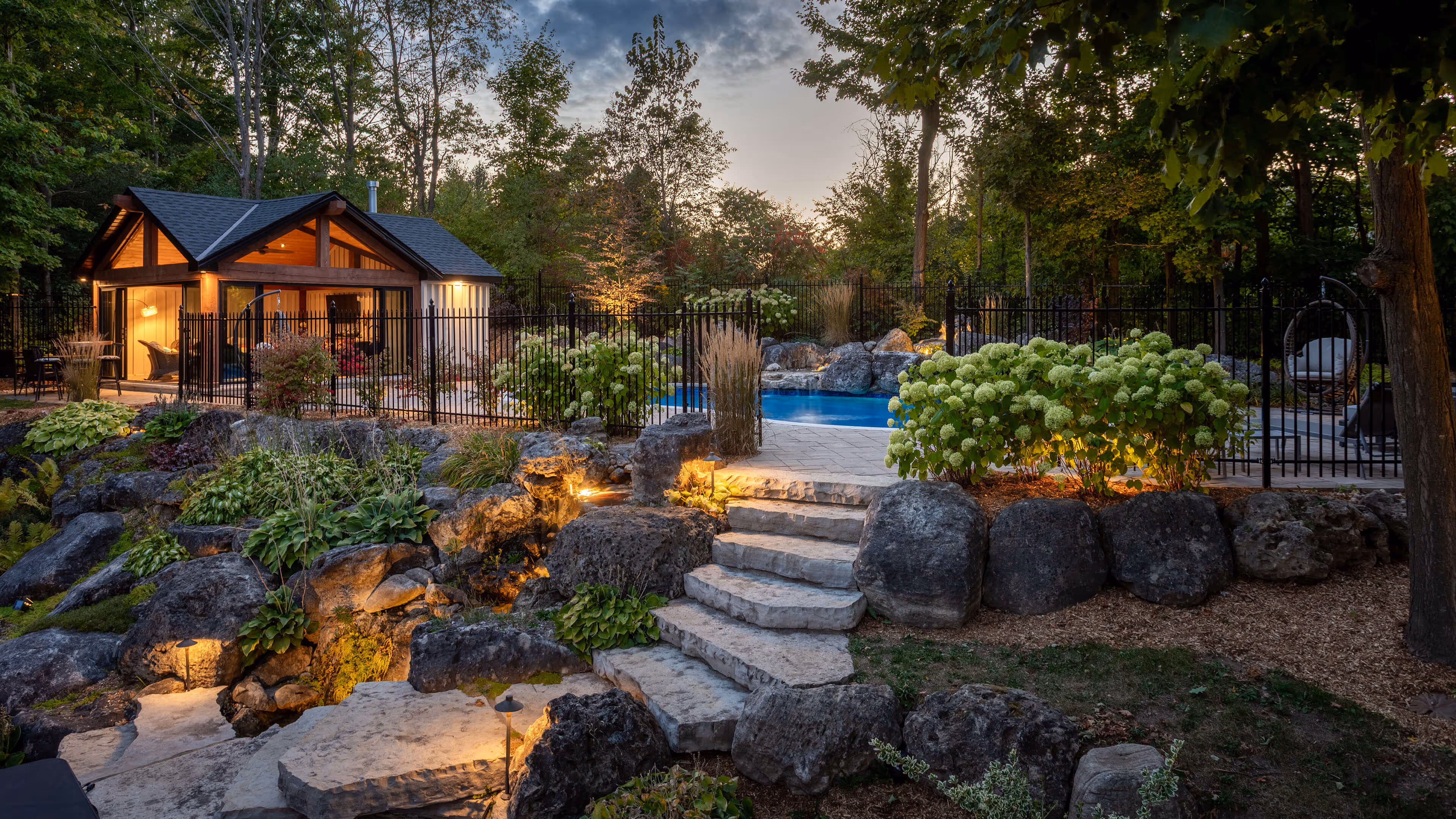 backyard landscaping with pool featureing waterfalls flowing into the pool, cabana with fireplace