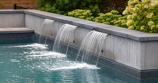 Cozy living room corner with a leather sofa, textured pillows, a cashmere throw, and a modern gas fireplace under a window.