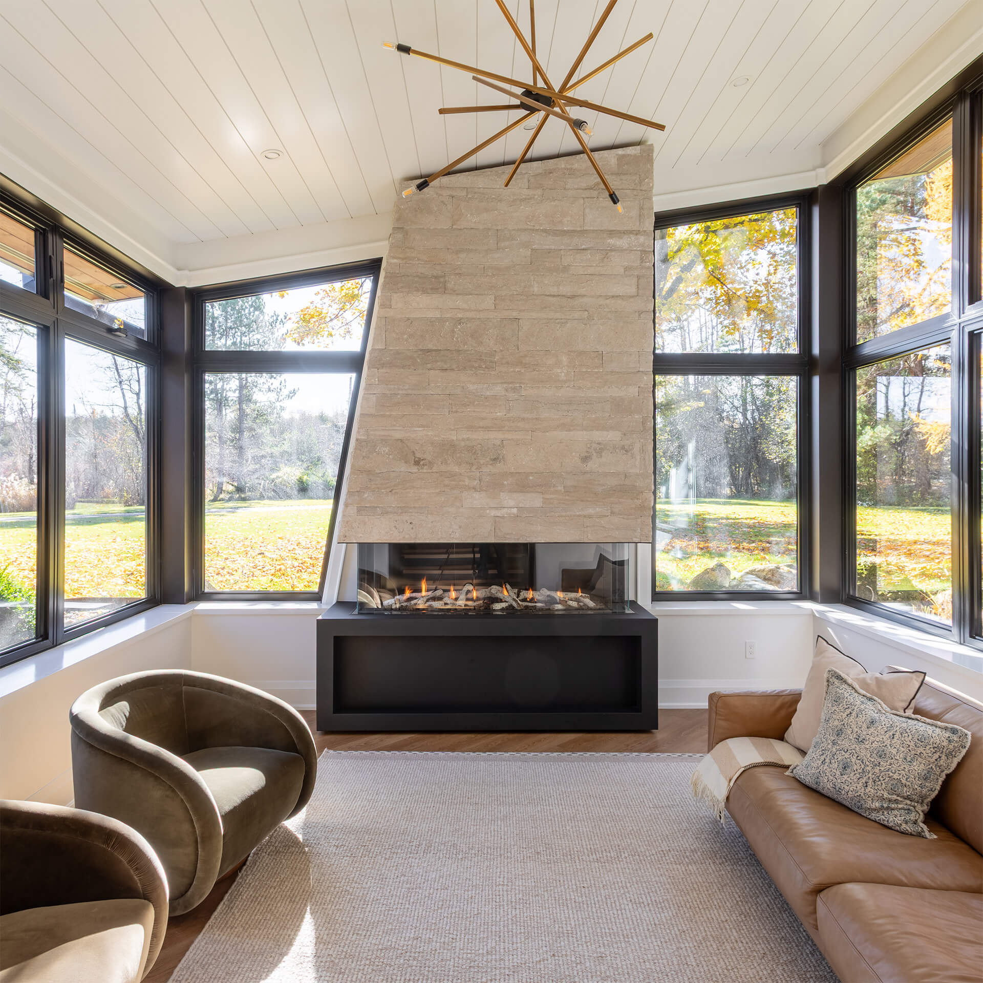 Wooden porch with gray pergola covered in green vines and purple flowers along a house with gray siding and white-framed doors and windows.