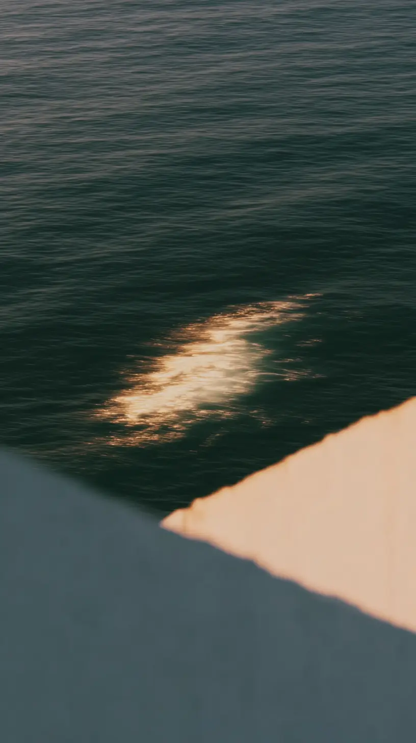Reflejo del sol dorado sobre el agua oscura del océano con una estructura en primer plano.