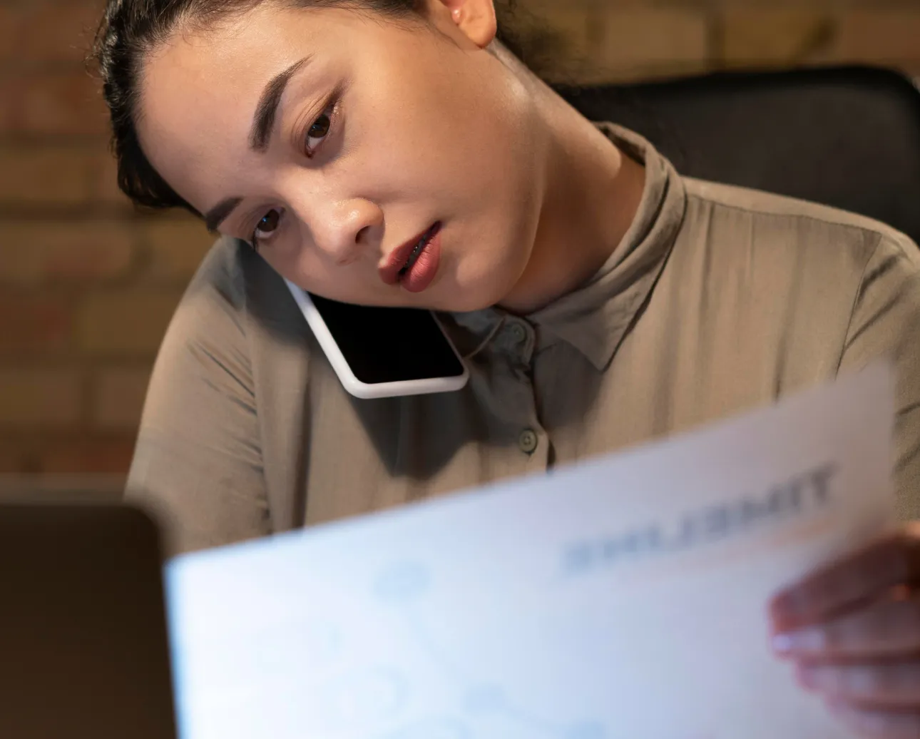 Woman multitasking on phone while reviewing documents