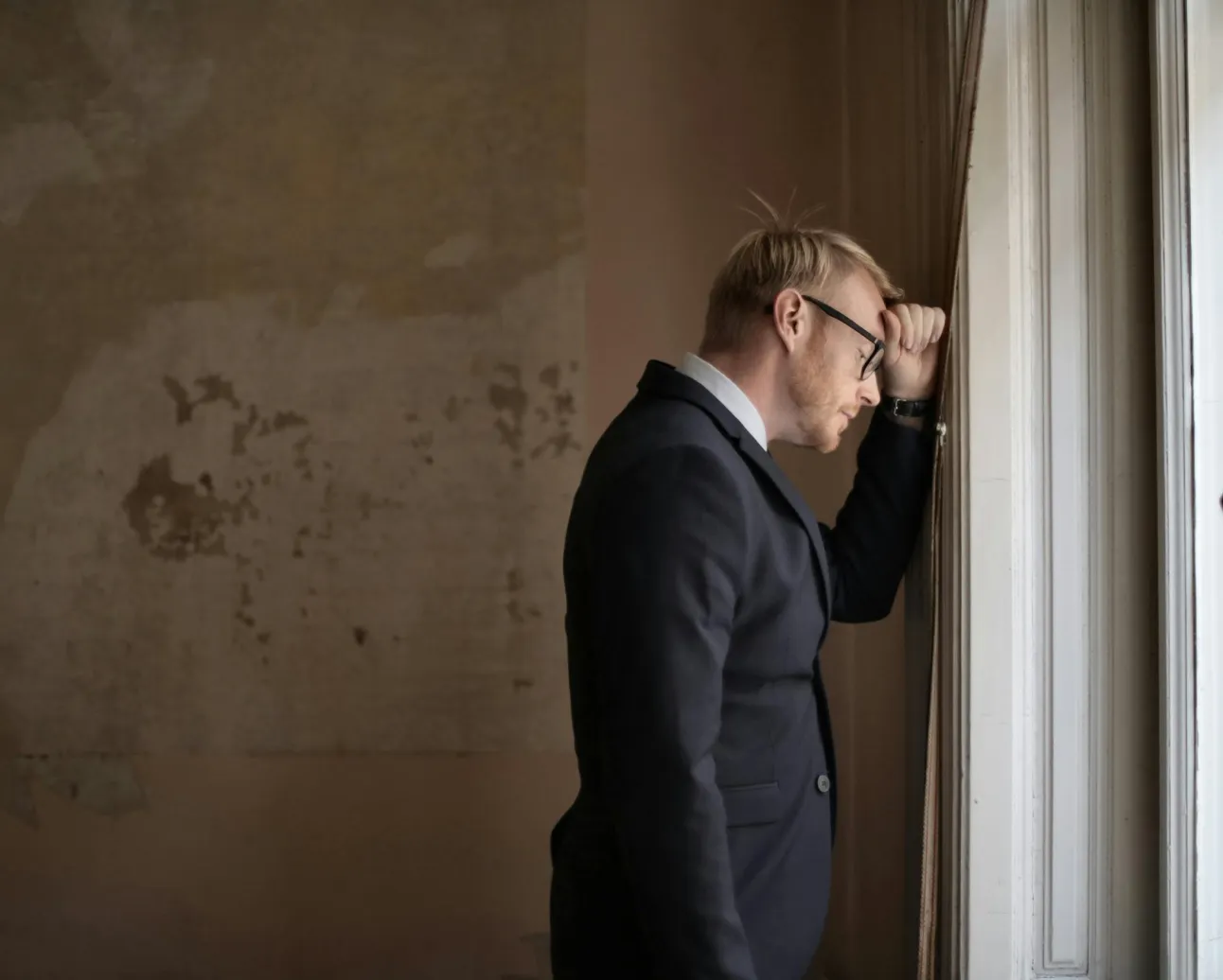 Person leaning against window in frustration