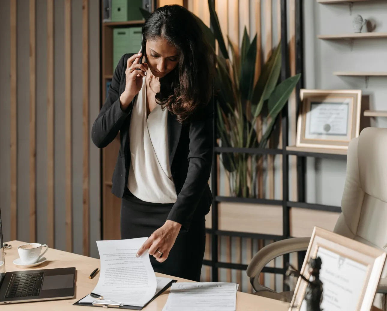 Businesswoman talking on phone and checking paperwork.
