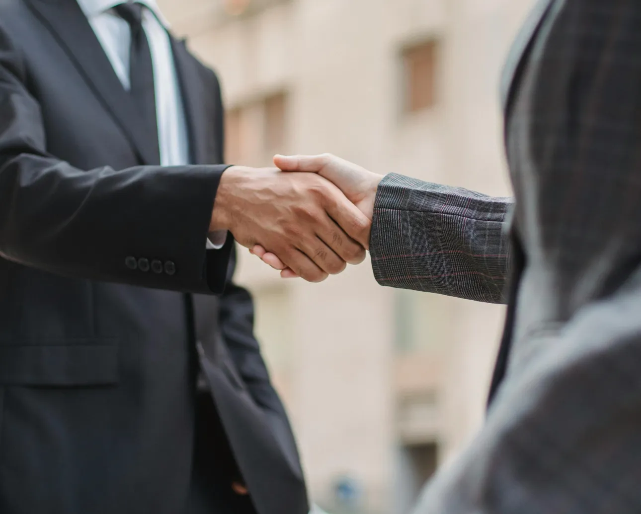 Two people shaking hands in business attire.
