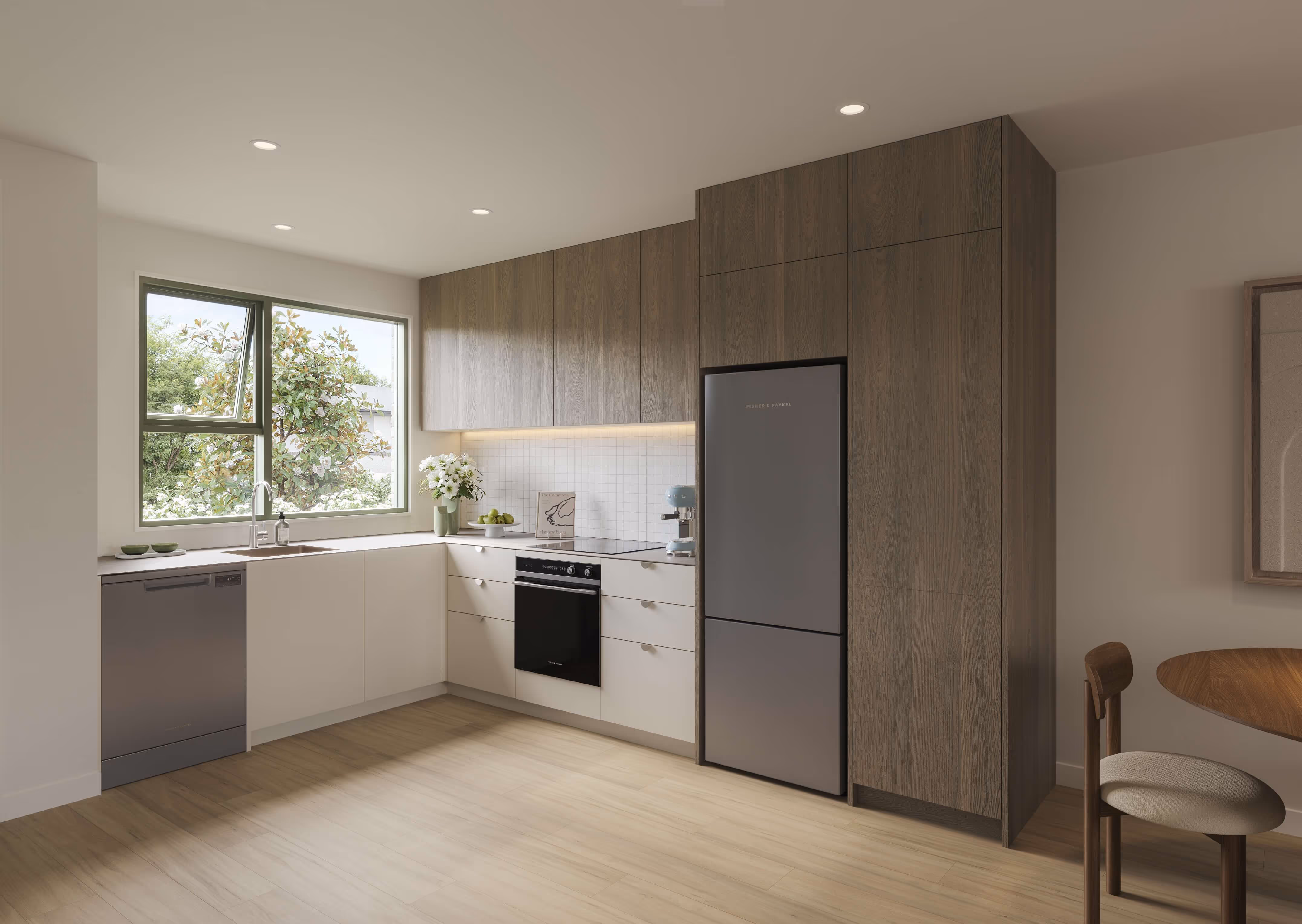 Modern kitchen with light wood flooring, white lower cabinets, dark wood upper cabinets, stainless steel refrigerator and dishwasher, and a window showing greenery outside.
