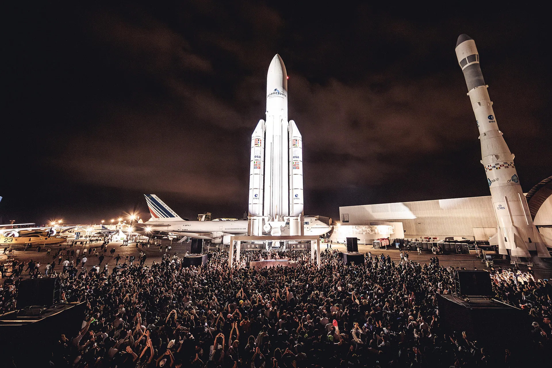 A crowd of people standing in front of a space shuttle.
