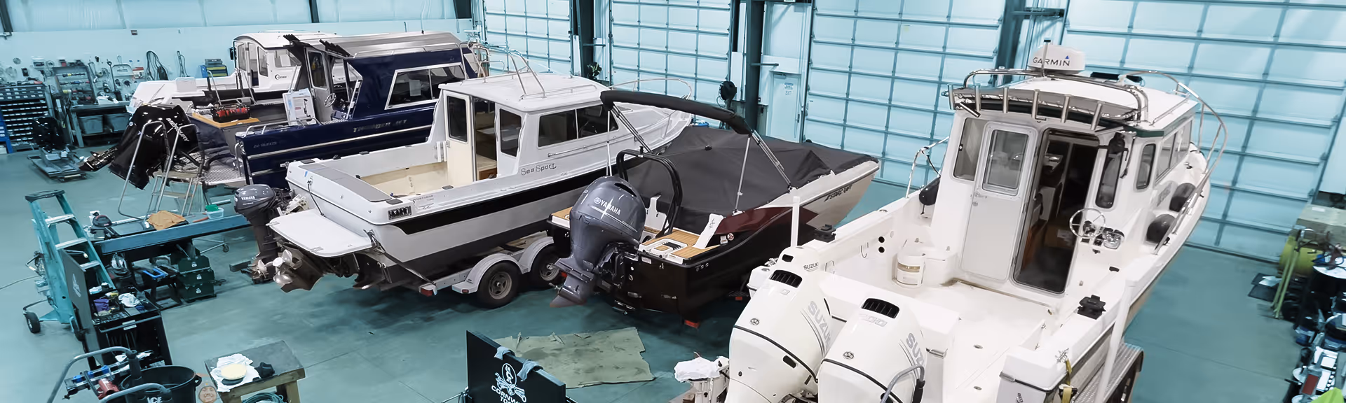 Interior of a marine service shop with multiple boats on trailers and various marine equipment.