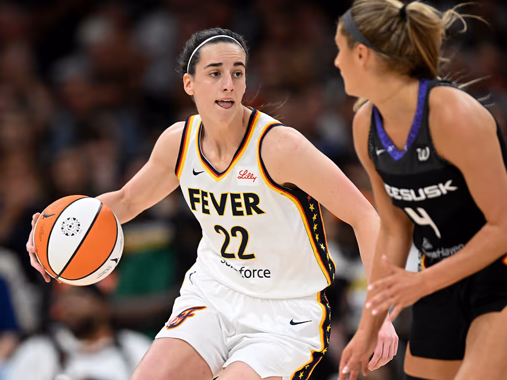 Indiana Fever player dribbles the ball up the court while being guarded by an opposing defender during a WNBA game.