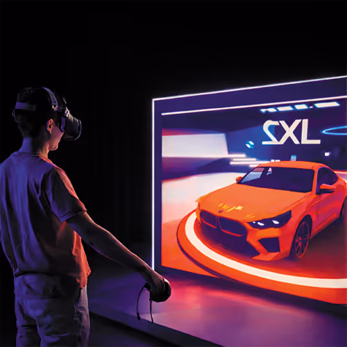 Person using a VR headset and controller interacting with a virtual orange sports car displayed on a screen in a dark room.