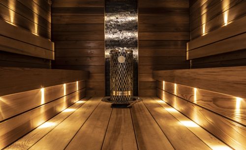 Puinen sauna, jossa on penkit molemmin puolin ja keskellä kiuas kivetäytteisellä säiliöllä.