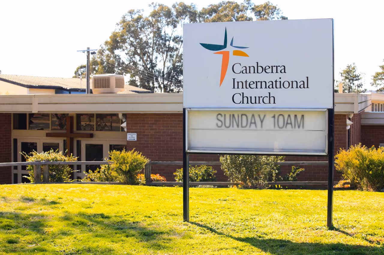  A photo of the front entry sign at Canberra International Church, with green grass on a sunny day. 