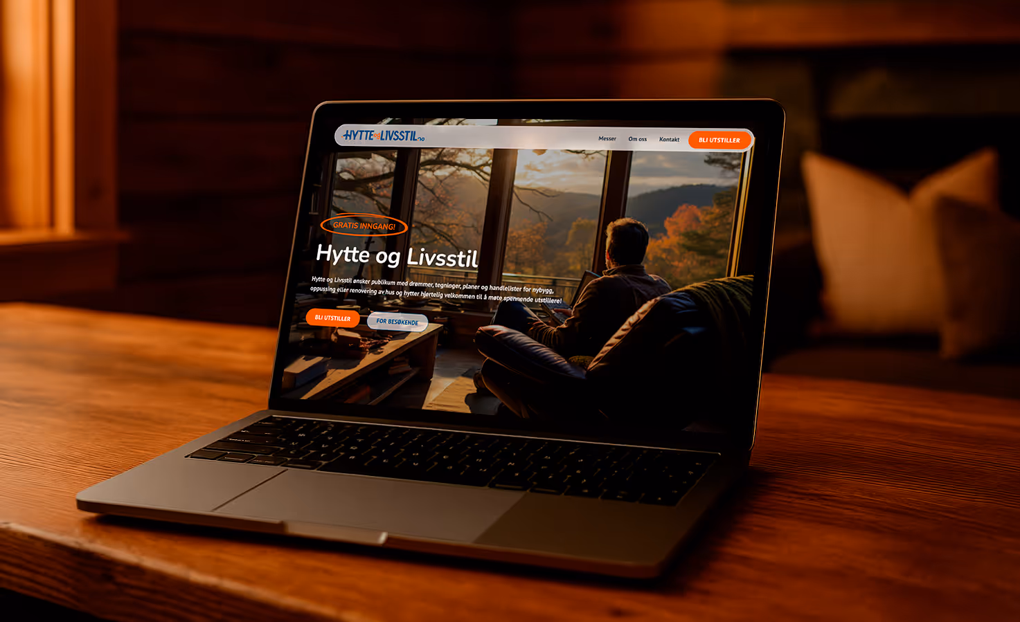 Laptop on wooden table displaying a website with a person sitting on a couch looking out large windows at an autumn landscape.