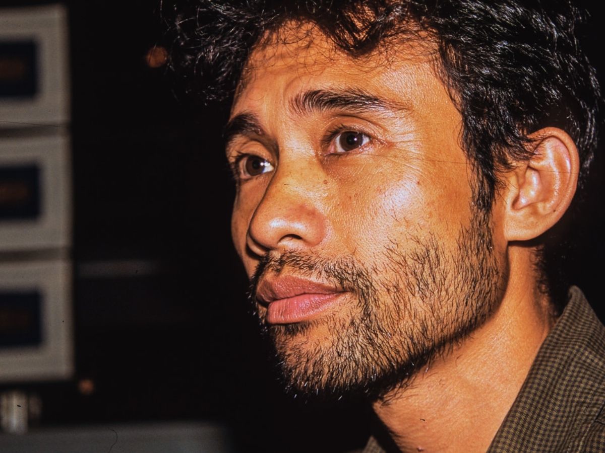 Close-up profile of a man with short curly hair and a beard looking thoughtfully to the side.