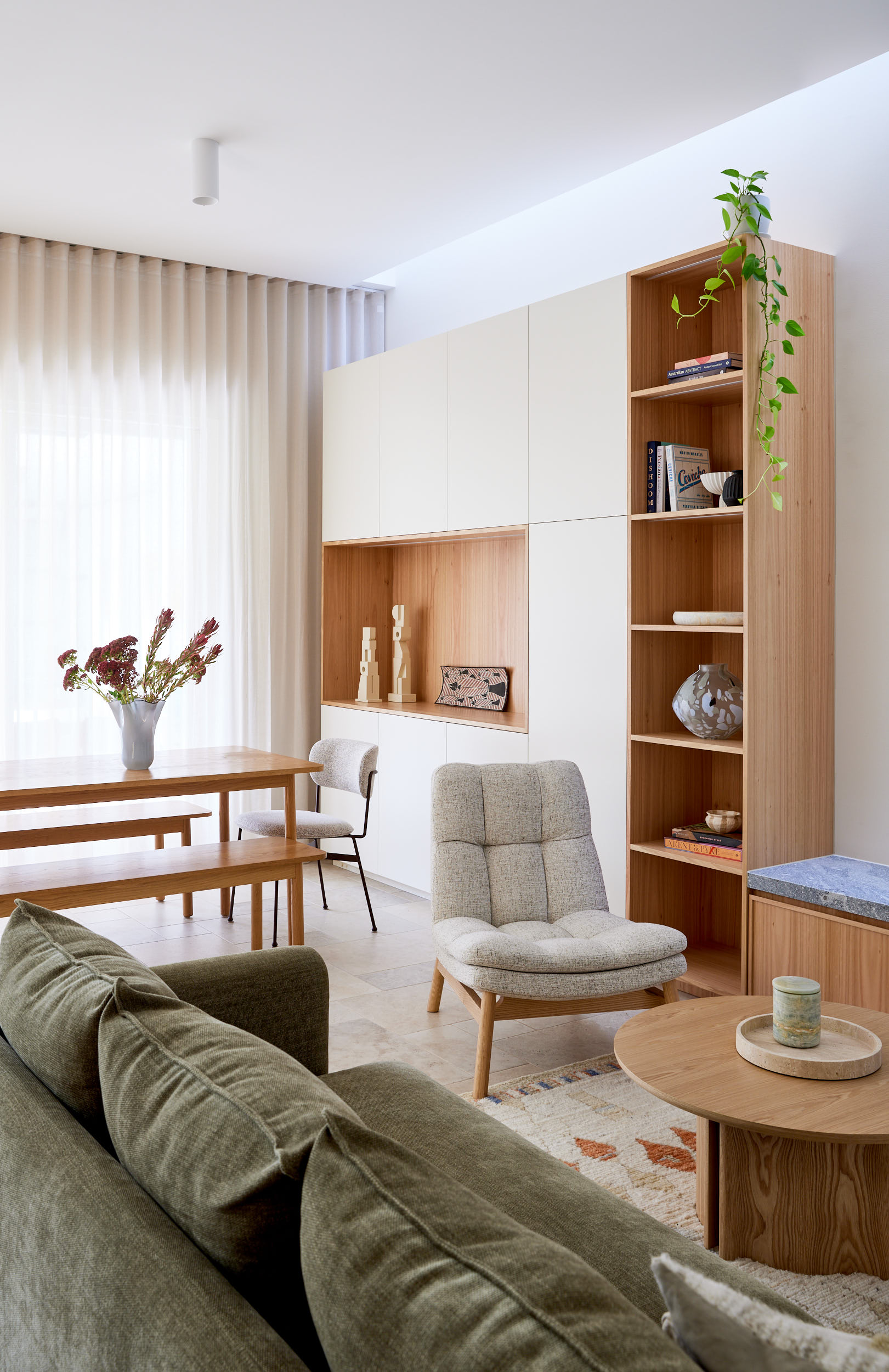 Beige sofa with a green square pillow and a beige-and-white striped rectangular pillow, with an abstract floral painting hanging above.