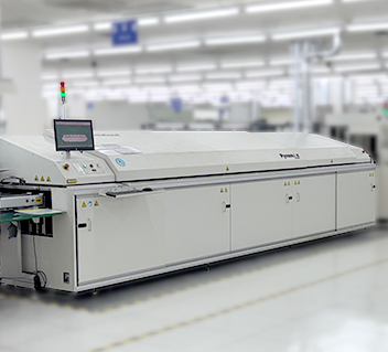 Large white industrial reflow soldering machine in a bright electronics factory.