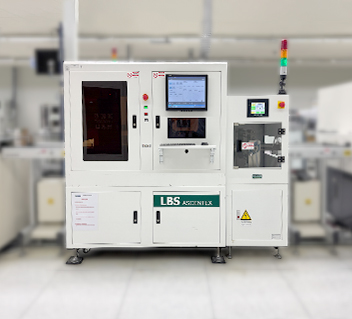 White industrial laser engraving machine with screens and control panel in a manufacturing setting.